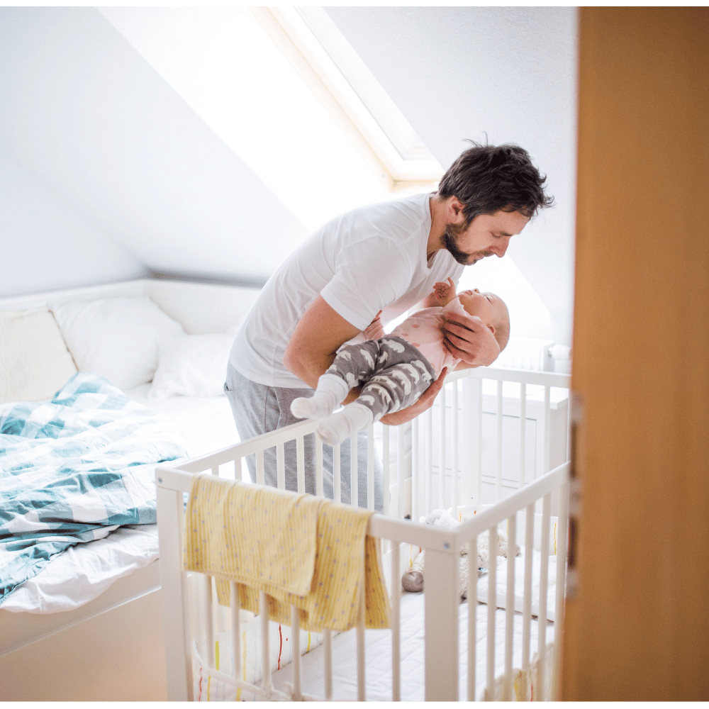 Father placing infantin bed